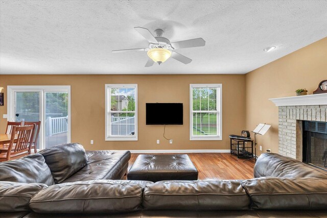 4603 Stonebridge Dr, Champaign, IL 61822 - living area featuring a textured ceiling, wood finished floors, a ceiling fan, and a brick fireplace