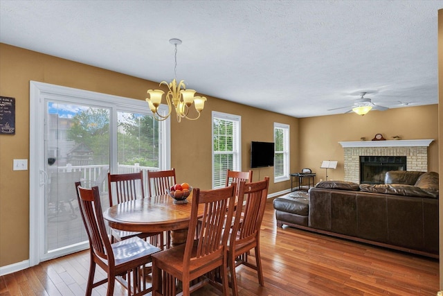 4603 Stonebridge Dr, Champaign, IL 61822 - dining space featuring a textured ceiling, baseboards, wood-type flooring, ceiling fan with notable chandelier, and a brick fireplace