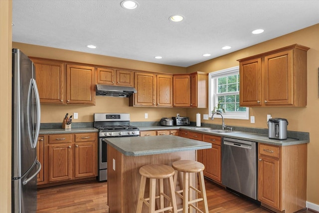 4603 Stonebridge Dr, Champaign, IL 61822 - kitchen featuring a center island, under cabinet range hood, a sink, wood finished floors, and appliances with stainless steel finishes