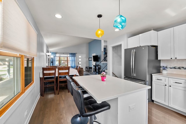 kitchen featuring a center island, lofted ceiling, wood finished floors, and tasteful backsplash