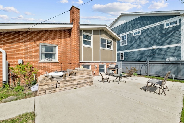 back of house featuring a chimney, a patio area, and brick siding