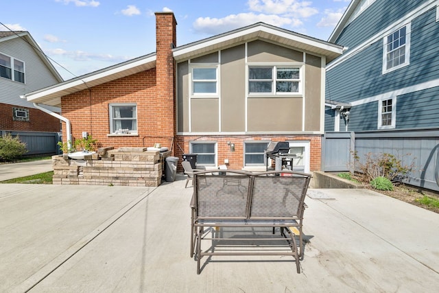 back of property with outdoor dining space, brick siding, stucco siding, a chimney, and a patio