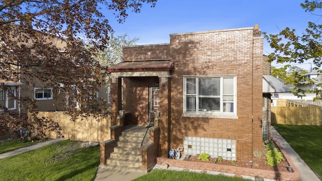 view of front facade featuring fence, a front yard, and brick siding