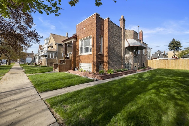 view of side of property with brick siding, fence, a residential view, and a lawn