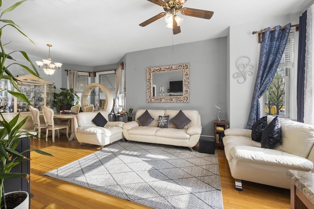 living area featuring wood finished floors and ceiling fan with notable chandelier