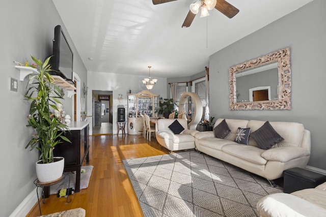 living room with baseboards, hardwood / wood-style flooring, and ceiling fan with notable chandelier