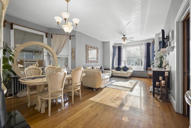 dining area featuring radiator heating unit, light wood-style flooring, and ceiling fan with notable chandelier