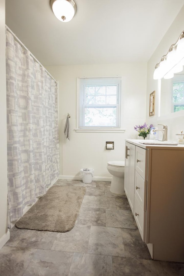 518 N Hartwell St, Gilman, IL 60938 - bathroom featuring vanity, toilet, a shower with shower curtain, stone finish floor, and baseboards