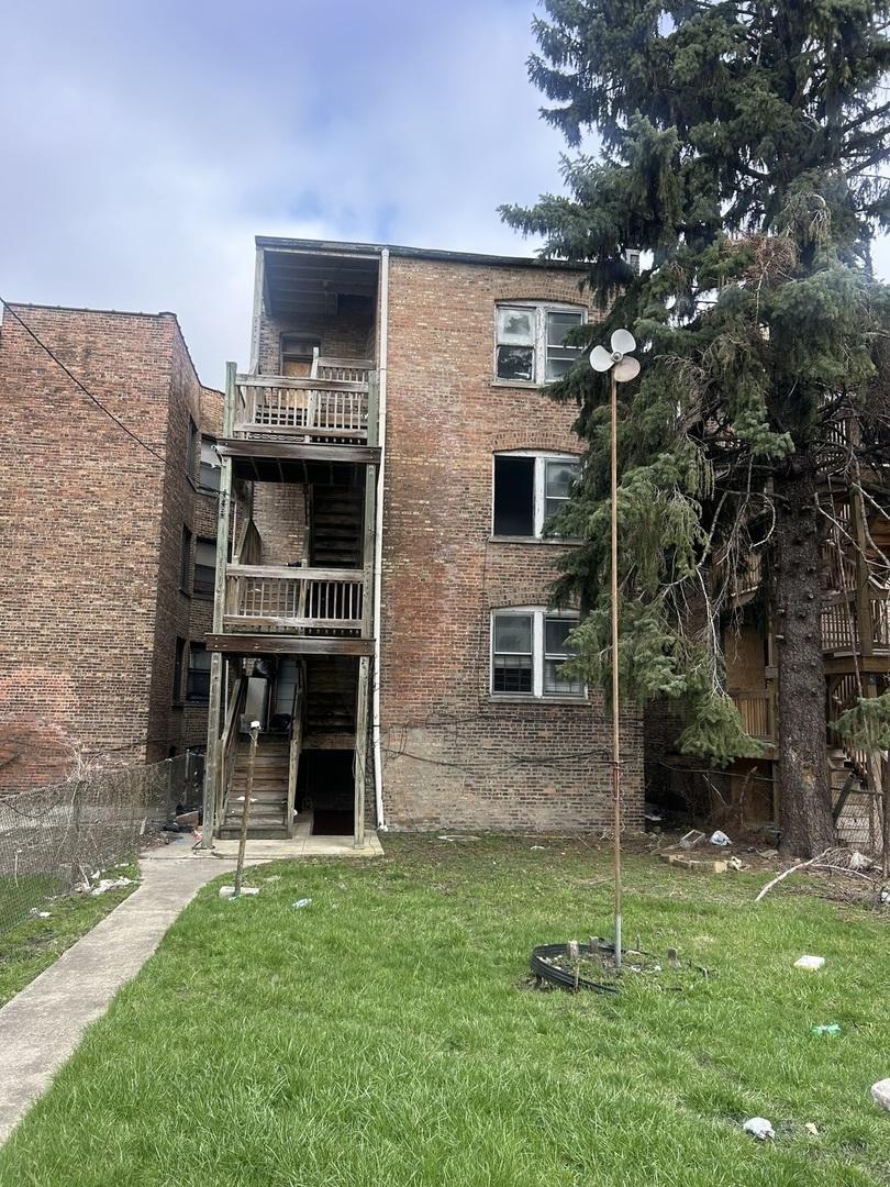 back of property with a lawn, stairs, and brick siding