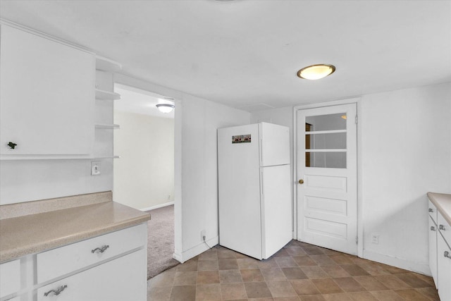 kitchen featuring freestanding refrigerator, open shelves, light countertops, and white cabinets