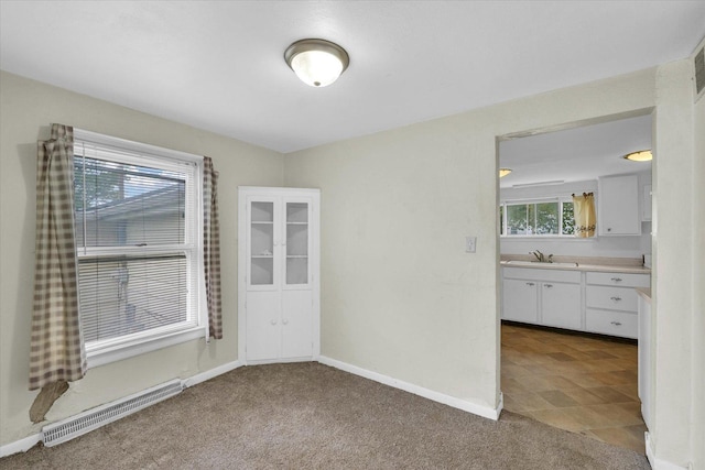 unfurnished dining area featuring a sink, carpet floors, baseboards, and visible vents