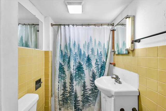 bathroom featuring a sink, tile walls, toilet, and visible vents