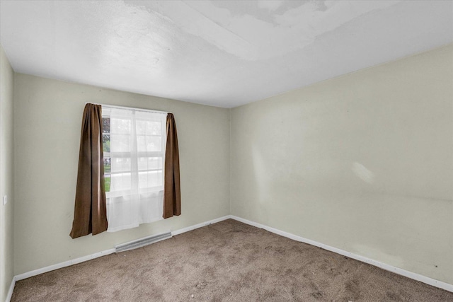 carpeted empty room featuring visible vents and baseboards