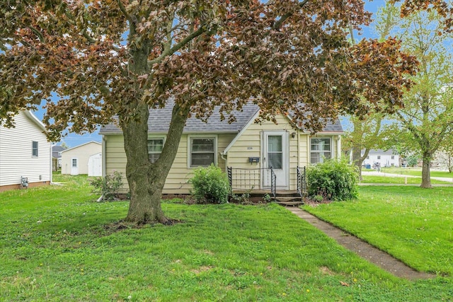 view of front of home with roof with shingles and a front yard