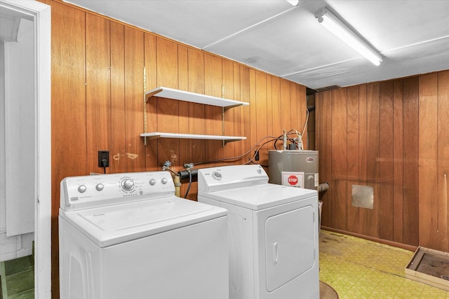 washroom with light floors, independent washer and dryer, gas water heater, wooden walls, and laundry area
