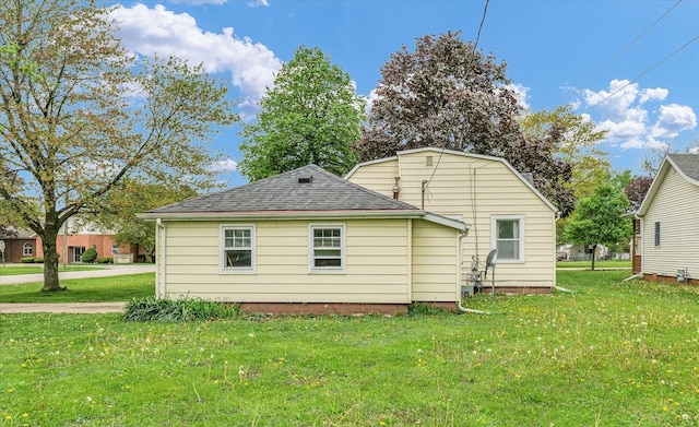 back of house featuring a shingled roof and a yard