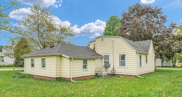back of property with a yard, roof with shingles, and cooling unit