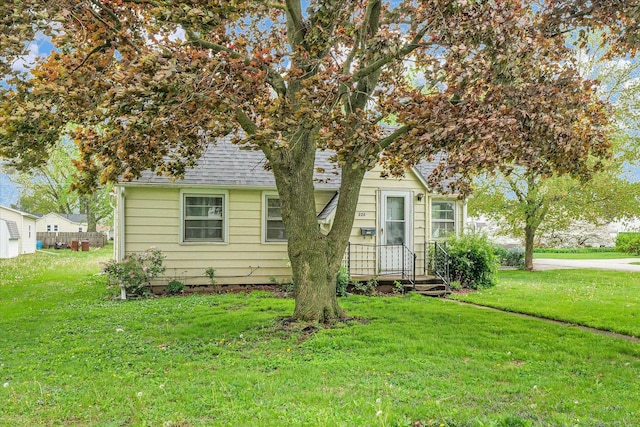 view of front of house featuring a shingled roof and a front yard
