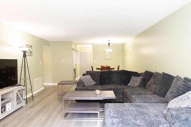 living area with baseboards, visible vents, and light wood finished floors