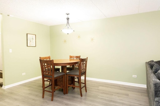 dining area featuring baseboards and light wood-style flooring