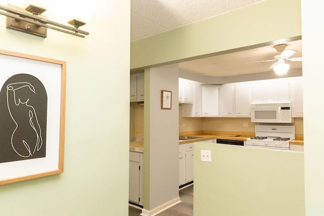 kitchen with wood finished floors, white appliances, light countertops, white cabinets, and a ceiling fan