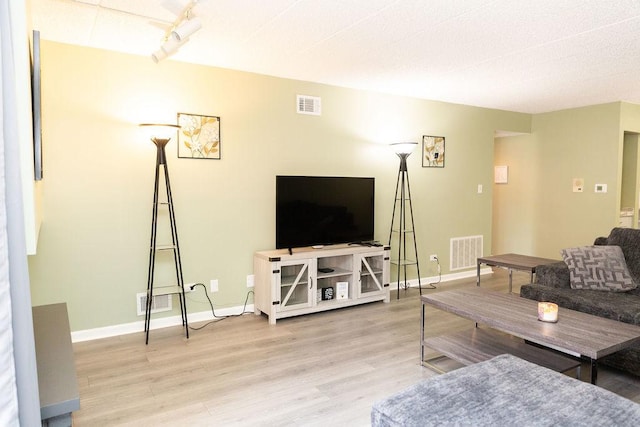 living area with baseboards, visible vents, wood finished floors, and rail lighting