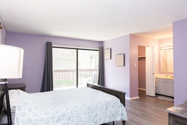 bedroom featuring access to exterior, baseboards, a textured ceiling, wood finished floors, and ensuite bathroom