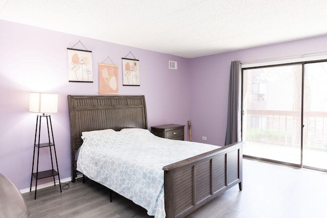 bedroom with wood finished floors, access to exterior, baseboards, visible vents, and a textured ceiling