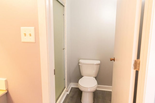 full bath with toilet, a stall shower, wood finished floors, and baseboards