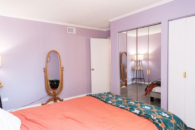 bedroom featuring wood finished floors, multiple closets, baseboards, visible vents, and crown molding