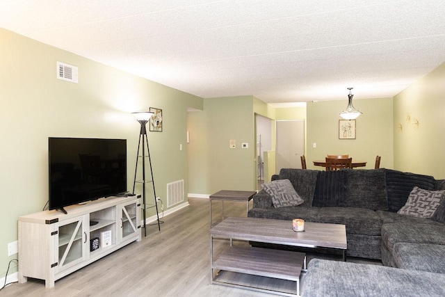 living room featuring baseboards, visible vents, and light wood-style floors