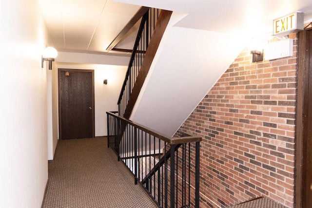 stairs featuring brick wall and carpet flooring