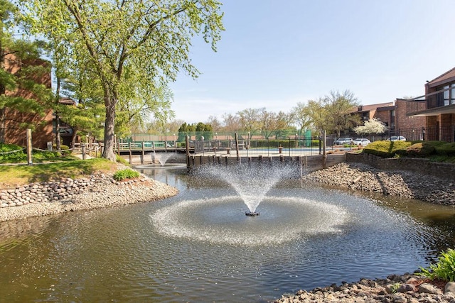 surrounding community with a water view and fence