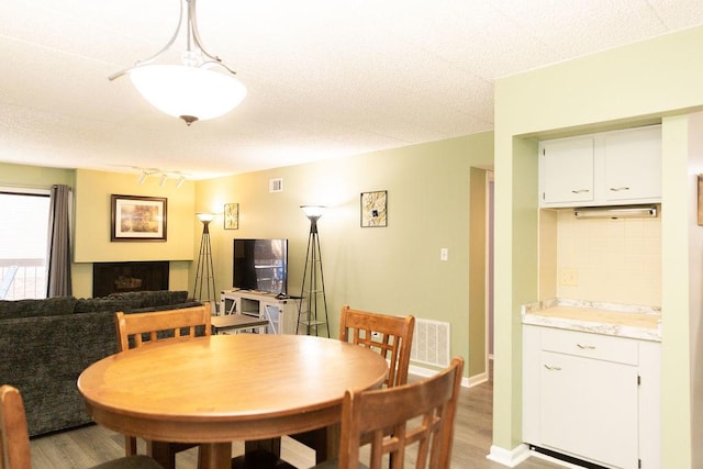 dining space featuring light wood finished floors, visible vents, and a fireplace