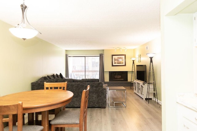 dining room featuring visible vents, light wood-type flooring, and a fireplace with raised hearth