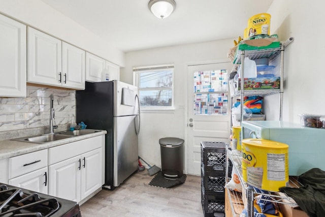 2122 Foster St, Evanston, IL 60201 - kitchen with tasteful backsplash, white cabinets, a sink, freestanding refrigerator, and light wood finished floors