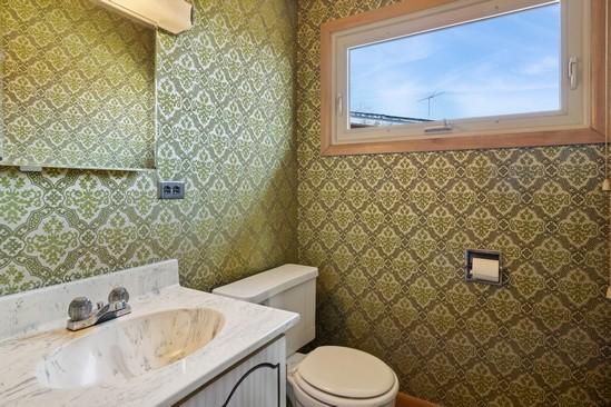 half bathroom with toilet, wallpapered walls, a wealth of natural light, and vanity