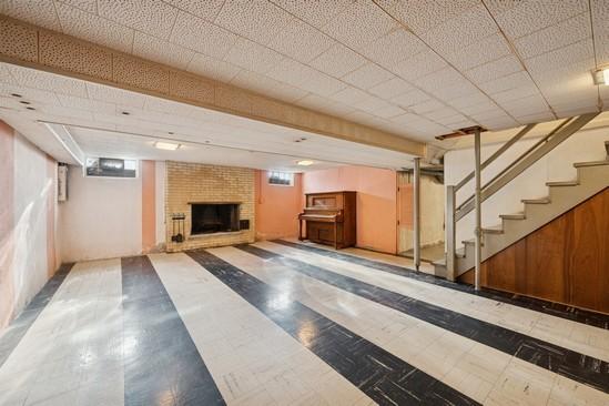 finished basement with a brick fireplace and stairs