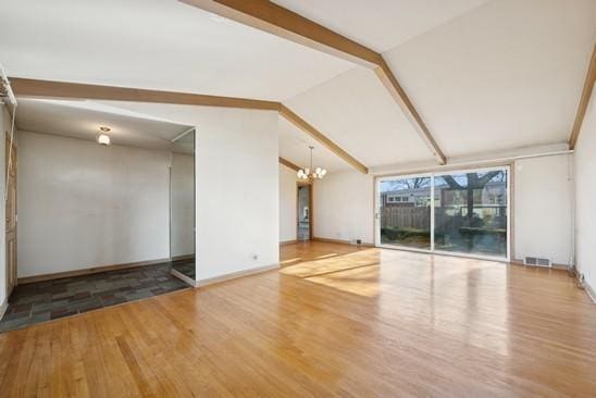 spare room featuring visible vents, baseboards, an inviting chandelier, wood finished floors, and vaulted ceiling with beams