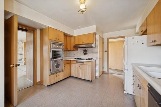 kitchen with stainless steel appliances, under cabinet range hood, light countertops, backsplash, and a sink