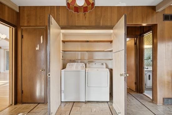 laundry room featuring visible vents, wood walls, laundry area, and washing machine and dryer