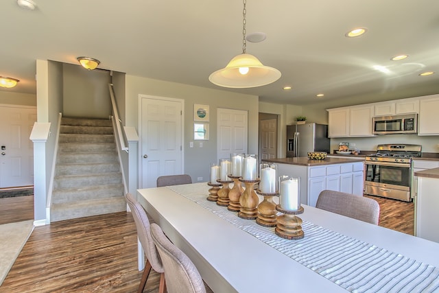 dining space with dark wood finished floors, recessed lighting, and stairs