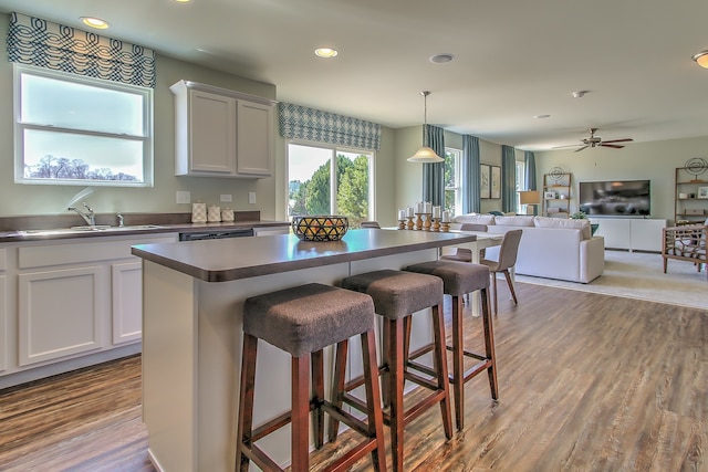 kitchen featuring a kitchen island, dark countertops, a kitchen bar, a sink, and open floor plan