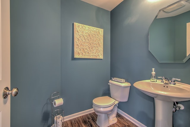 half bath with wood finished floors, toilet, and baseboards