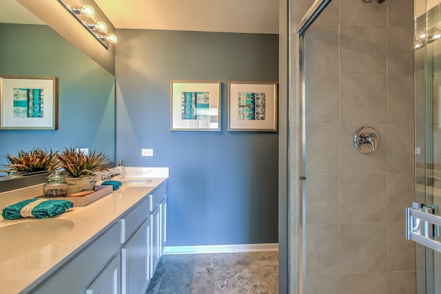 bathroom with baseboards, tiled shower, double vanity, and a sink