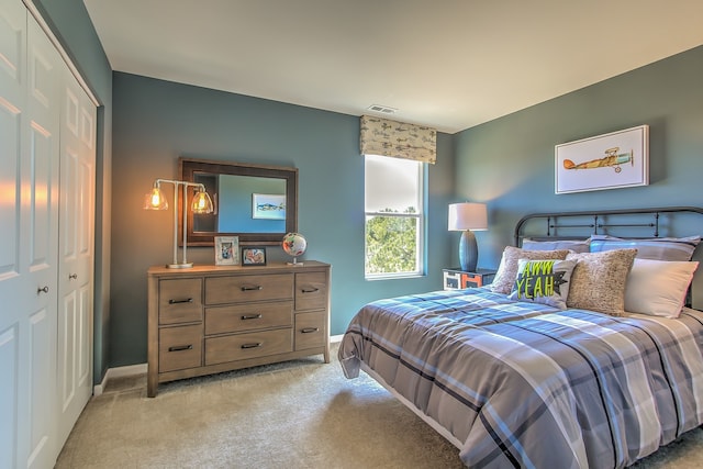 bedroom featuring light colored carpet, visible vents, baseboards, and a closet