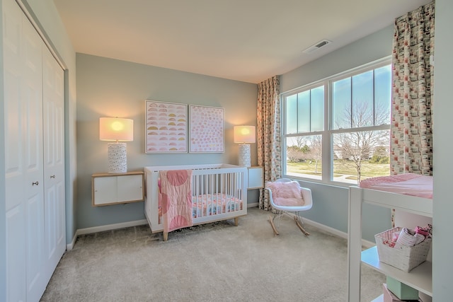 carpeted bedroom featuring a closet, visible vents, and baseboards