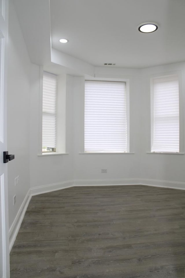 spare room with dark wood-style flooring, baseboards, visible vents, and recessed lighting