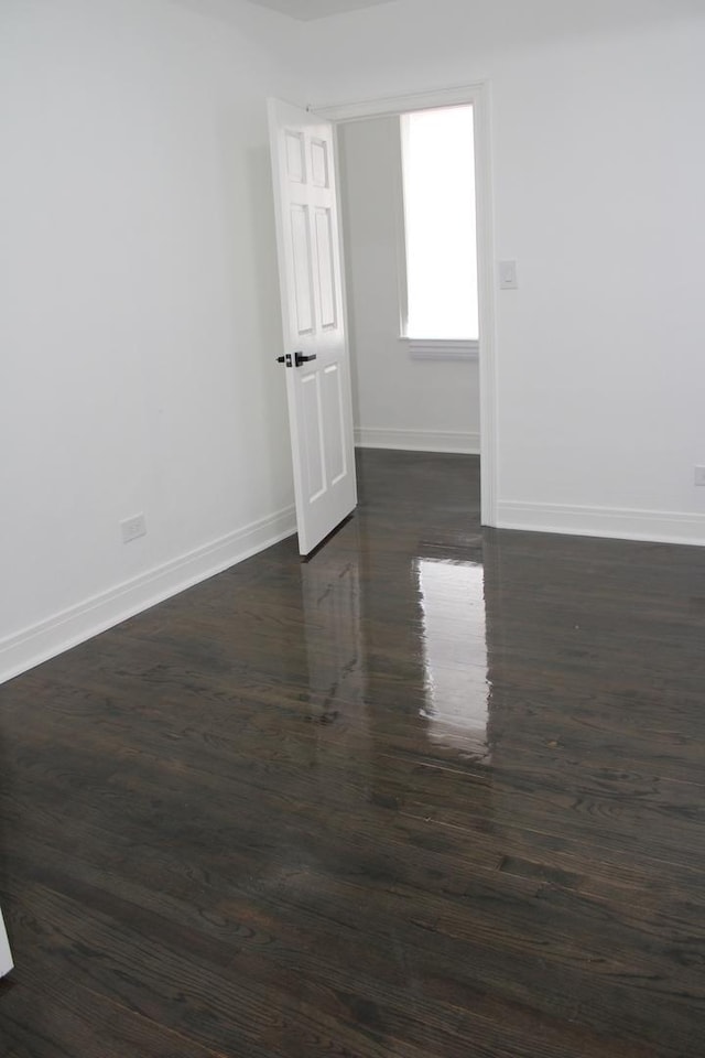 spare room featuring baseboards and dark wood-style flooring