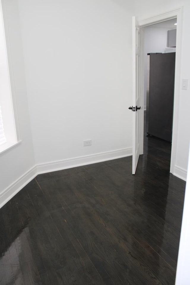 unfurnished room featuring baseboards and dark wood-style floors